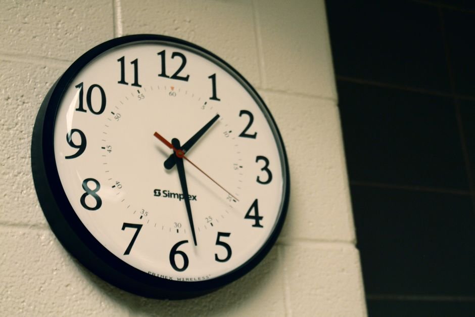 Simplex wall clock on a white brick wall, depicting time and simplicity.