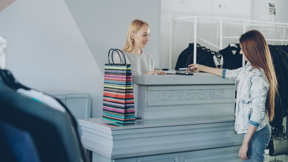 Customer interacting with cashier at boutique counter with shopping bags.