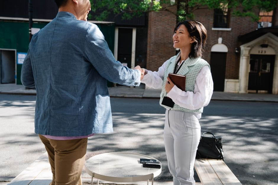Two individuals shaking hands on a city street, symbolizing business cooperation.