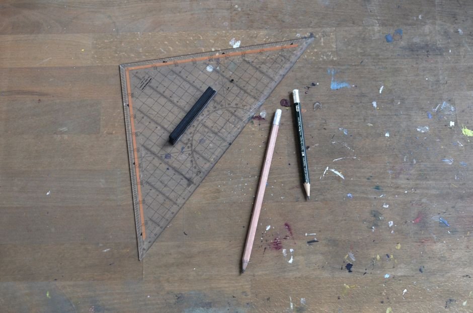 From above of old wooden table with pencils crayon and triangle ruler on engineering workplace