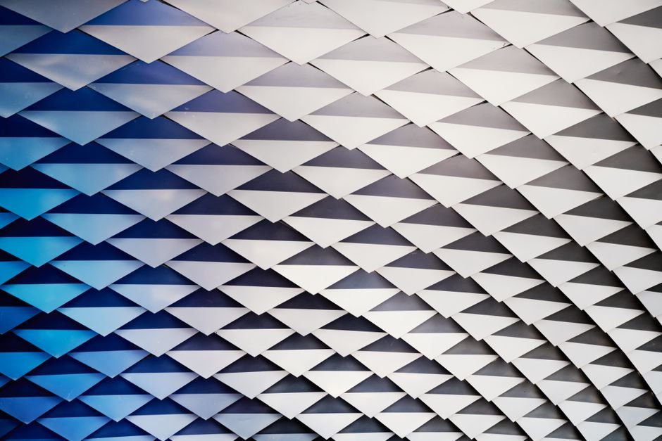 Abstract geometric ceiling with white structures and blue gradient lighting.
