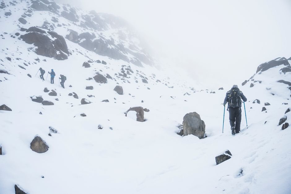 Hikers trekking through snowy mountainous terrain in winter, capturing the essence of adventure and exploration.