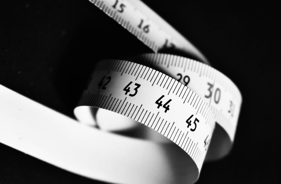Curved white measuring tape with numbers 15 to 45 on a dark background.