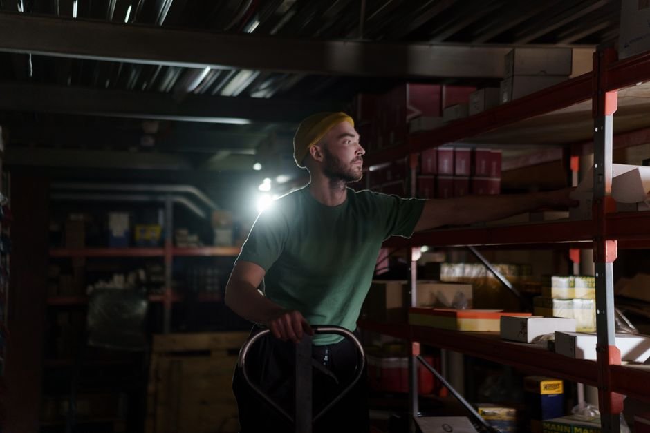 A dedicated worker organizing inventory on warehouse shelves with focused concentration.