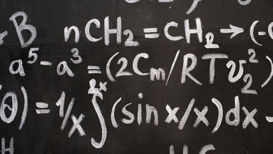 Close-up of complex equations on a chalkboard, showcasing chemistry and math symbols.