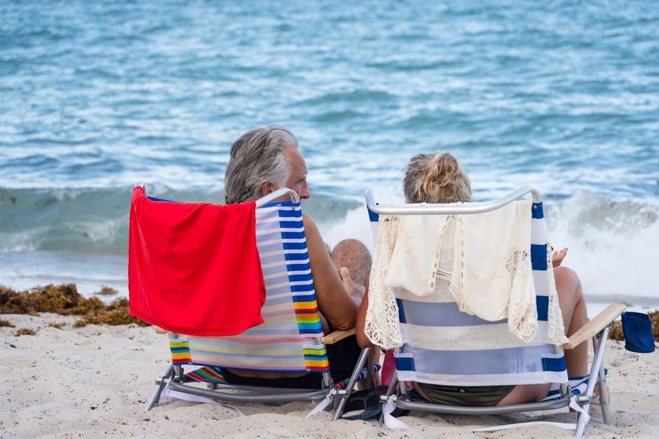 Senior couple relaxing on Miami Beach, enjoying the ocean view and summer sunshine.