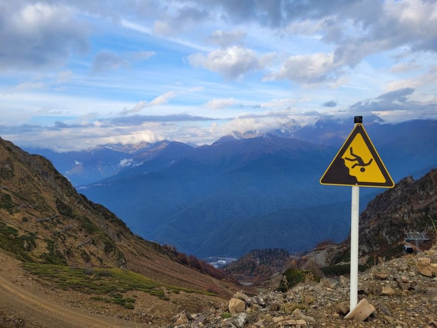 Breathtaking view of mountains with a warning sign indicating cliff danger. Ideal for adventure and travel themes.