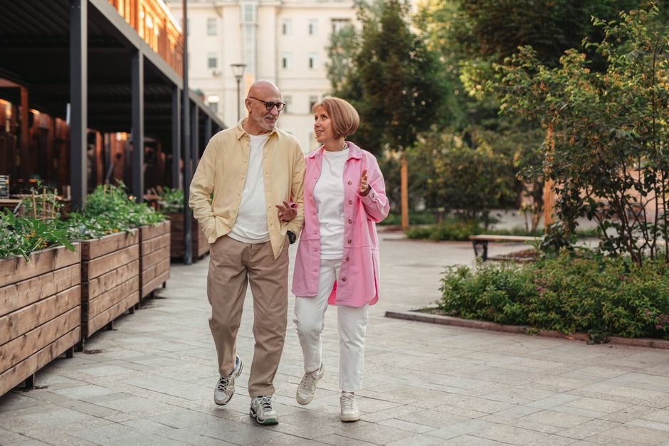 Happy senior couple walking together in a lush outdoor urban setting.
