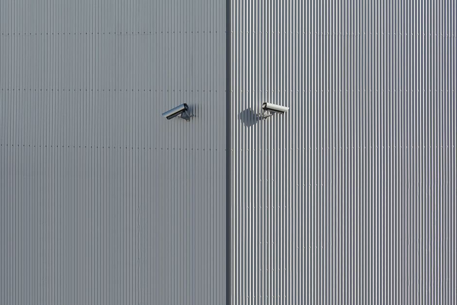 Corrugated metal wall with two mounted security cameras in a minimalist style.
