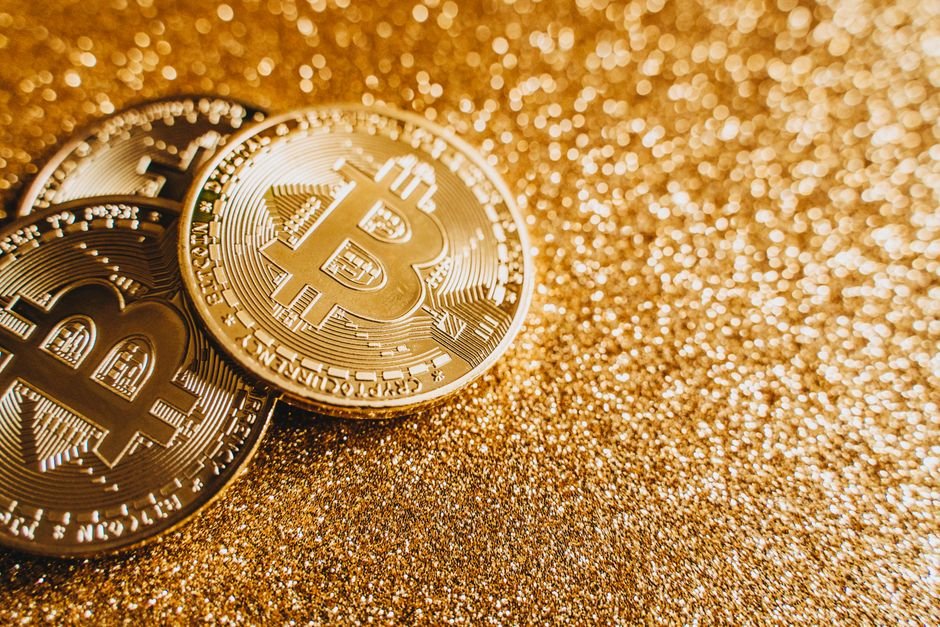 A close-up image of bitcoins placed on a sparkling gold glitter background, symbolizing cryptocurrency wealth.