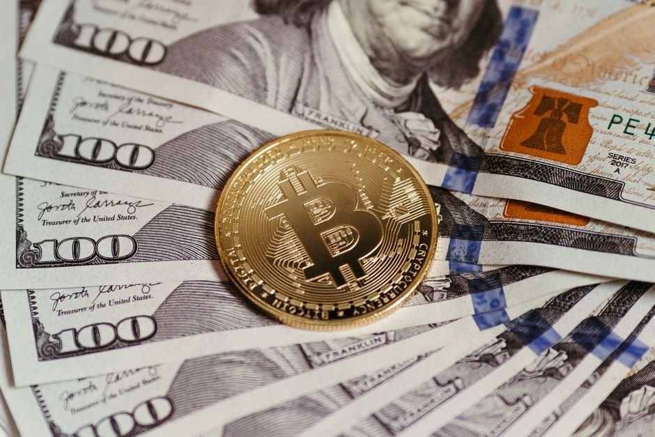 Gold Bitcoin coin resting on US dollar bills showcasing digital and traditional currency.