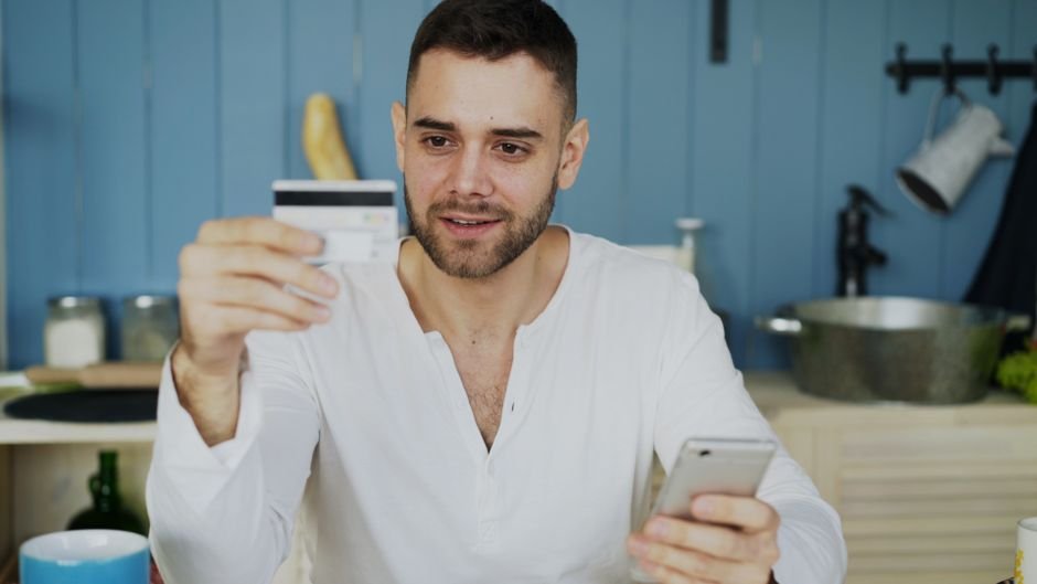 Man holding credit card and smartphone, shopping online at home.