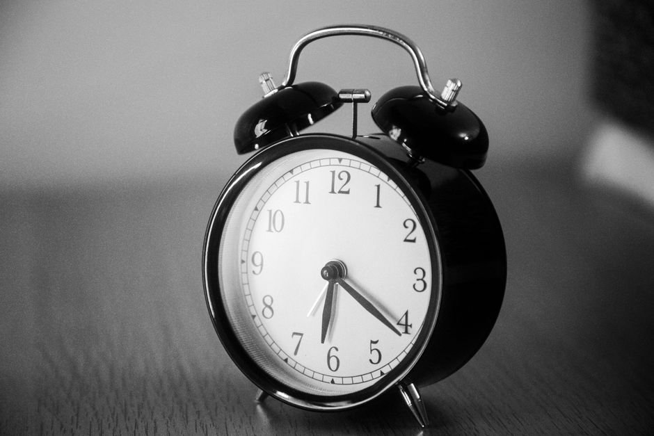 Close-up of a black vintage alarm clock showing precise time in grayscale.
