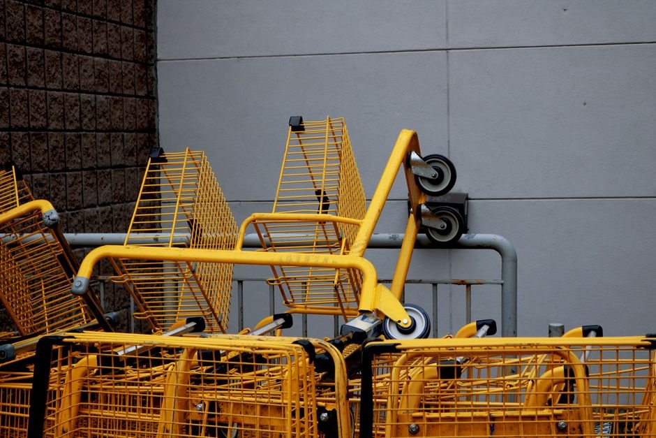 A stack of yellow shopping carts outside a building, showcasing industrial design.