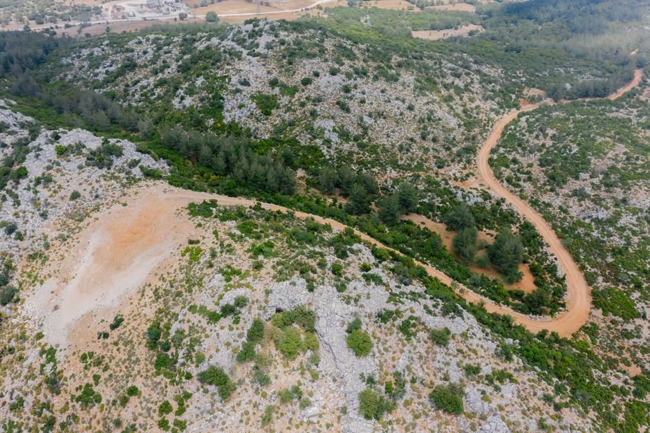 Aerial view highlighting a winding path through a rocky mountainous landscape with lush greenery.