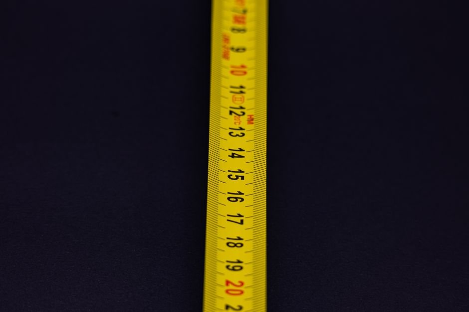 Detailed shot of a yellow measuring tape with numbers on a dark background.