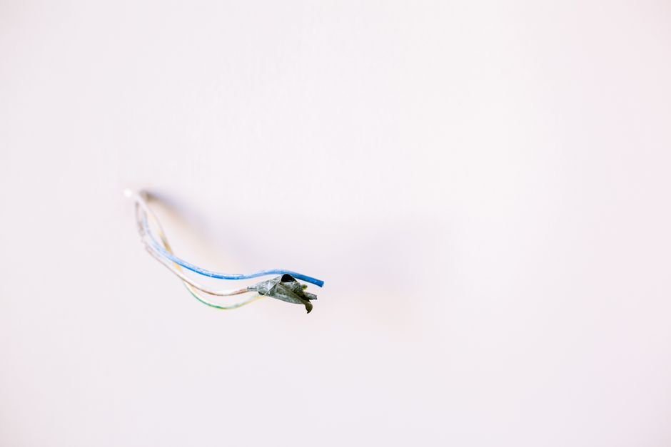 Loose electrical wires protruding from a white wall, ideal for home improvement concepts.