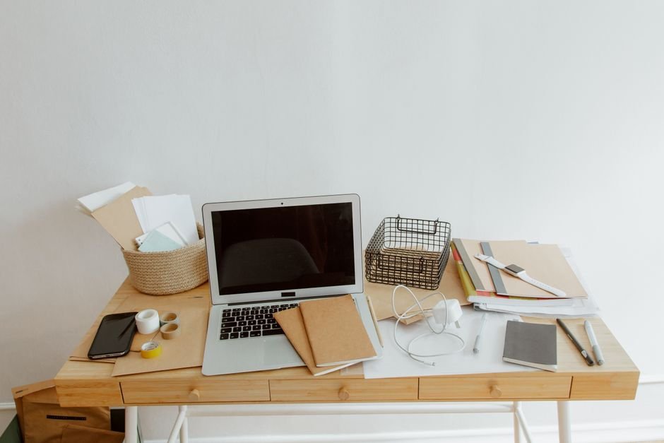 Clean and organized desk with a laptop, notebooks, and office supplies for productivity.