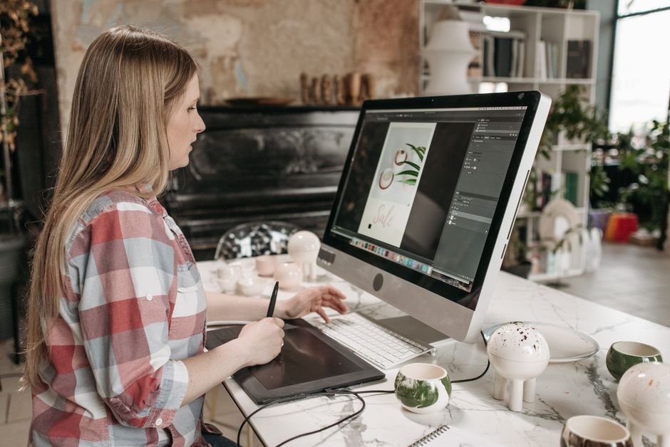 Woman using a digital drawing tablet in a stylish office workspace, focused on graphic design.
