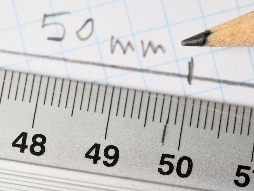 Detailed image of a ruler and pencil marking 50mm on graph paper.